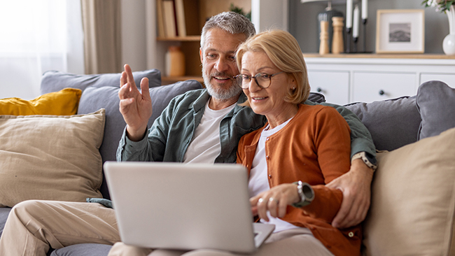 retired couple on sofa looking at laptop