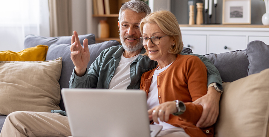 retired couple on sofa looking at laptop