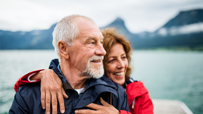 Two old couples hugging with lake in the background